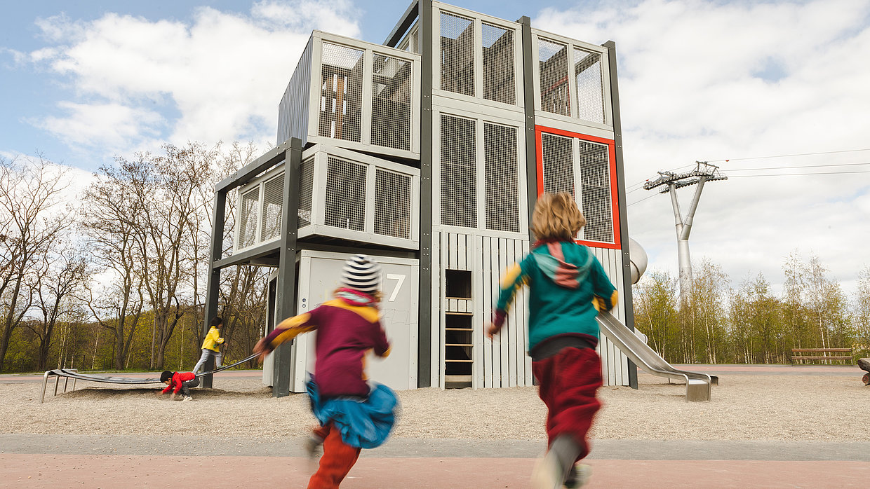 Zwei Kinder laufen auf den Spielplatz Elektropolis im Kienbergpark zu