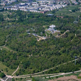 Luftbild vom grünen, baumbepflanzten Kienbergpark und dem angrenzenden Areal der Gärten der Welt