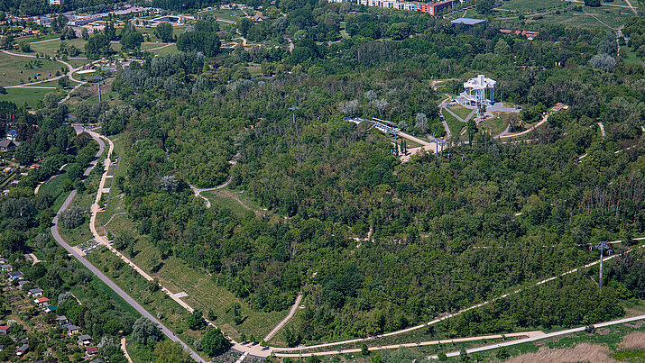 Luftbild vom grünen, baumbepflanzten Kienbergpark und dem angrenzenden Areal der Gärten der Welt
