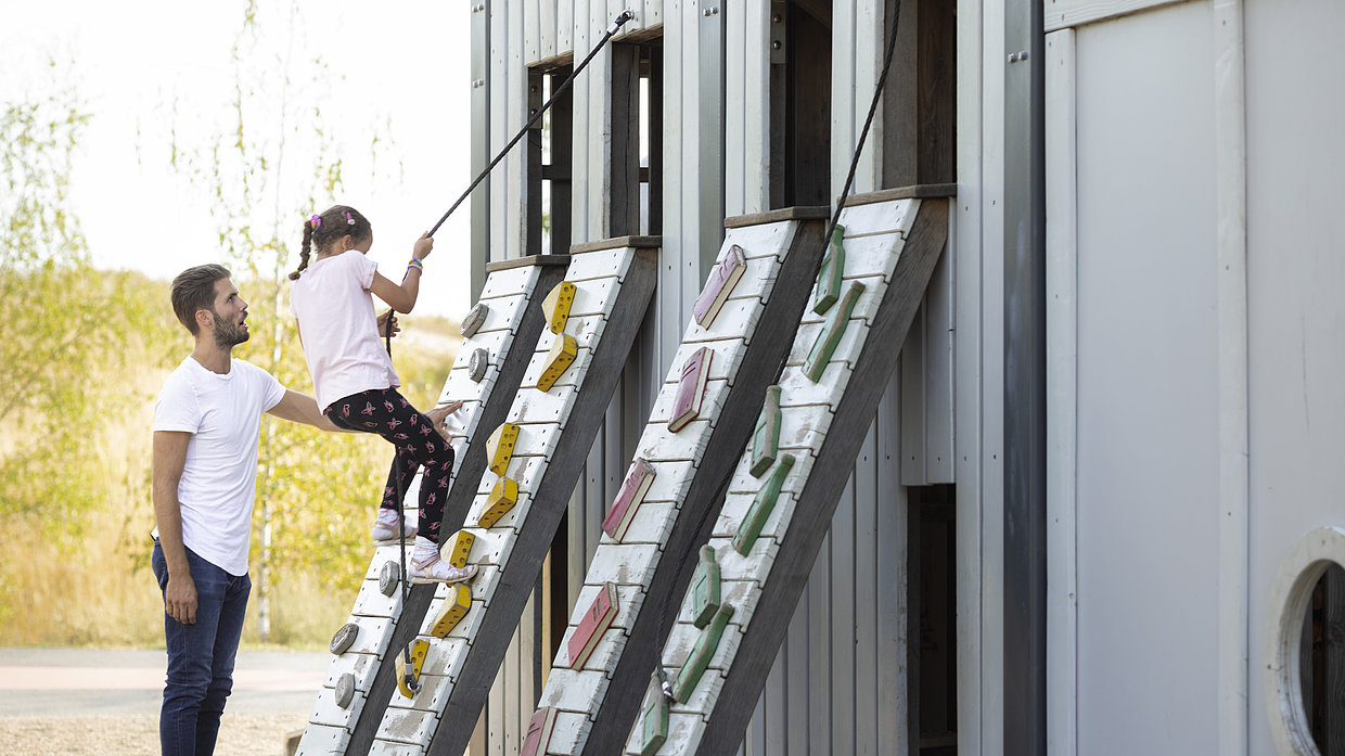 Ein Kind klettert an einem Seil eine Wand auf dem Spielplatz Elektropolis im Kienbergpark hoch